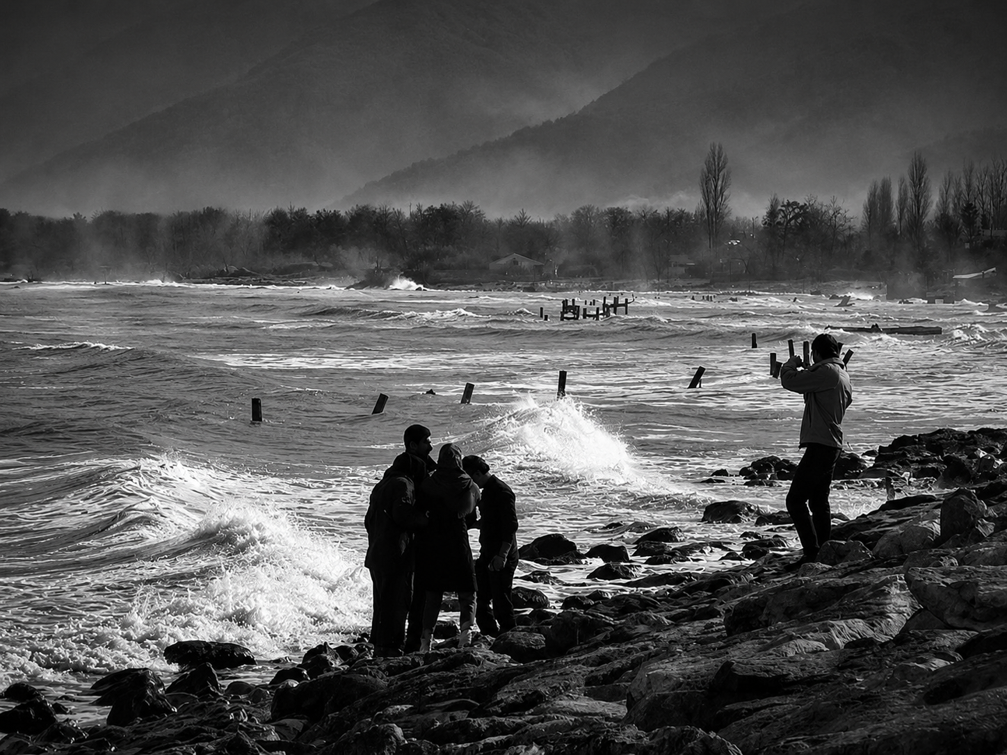 People standing beside a turbulent sea